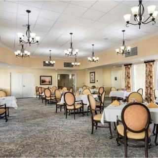 An elegant dining room with chandeliers and neatly arranged tables and chairs.