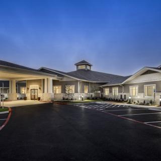 A well-lit building with a parking area at dusk.
