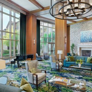 A luxurious hotel lobby featuring elegant seating, a grand chandelier, and a fireplace.