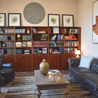 A cozy library room with bookshelves, leather seating, and a coffee table.