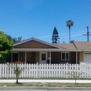 A suburban house with a white picket fence and palm trees.