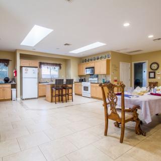 Spacious modern kitchen with an open dining area, featuring wooden cabinets and a tiled floor.