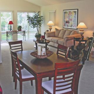 A cozy living room with a dining area featuring a wooden table, chairs, and a comfortable sofa.