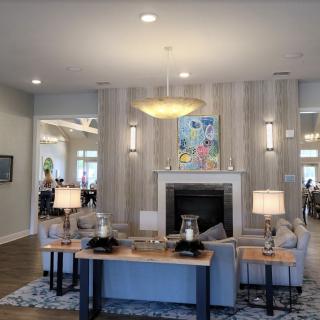 A modern living room with a stylish chandelier, cozy sofa, and elegant fireplace adorned with contemporary artwork.