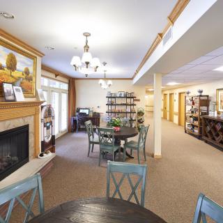 A cozy living and dining area featuring a fireplace, chandelier lighting, and wooden furniture.