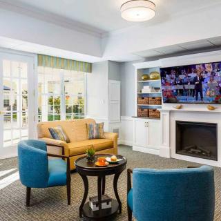 A modern living room with comfortable seating and a large television above the fireplace.