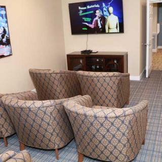 A cozy living room setup with patterned chairs facing a television, showcasing a comfortable and stylish interior design.