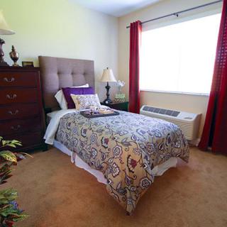 A cozy bedroom with a single bed, elegant decor, and natural light coming through the window.
