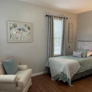 A cozy bedroom with a single bed, armchair, and tasteful decor.