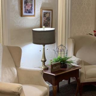 A cozy living room with beige chairs, a decorative lamp, and a small table accentuated by potted greenery.
