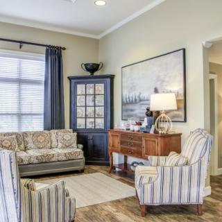 A cozy living room with striped armchairs and a decorative cabinet.