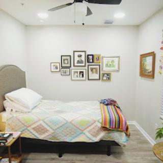 A cozy and well-decorated bedroom featuring a neatly made bed with colorful bedding and an array of framed pictures on the wall.