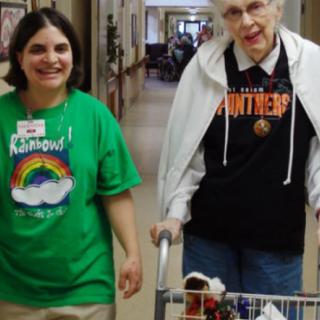 Two individuals walking in a hallway, with one providing assistance to the other.