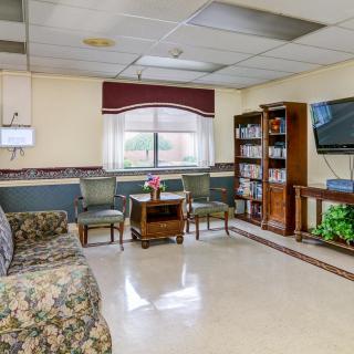 A cozy waiting room with comfortable seating, a large television, and bookshelves filled with reading materials.