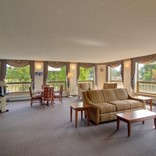 A spacious living room with large windows, furnished with a sofa, coffee table, and a dining area.