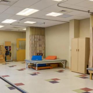A spacious physical therapy room equipped with exercise tools and a therapy bed.