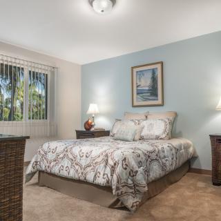 A cozy bedroom with a neatly made bed, two nightstands, and soft lighting.