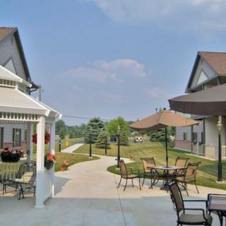 A sunny outdoor patio area with tables and chairs between two buildings.