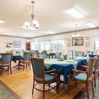 An inviting dining room with neatly set tables and comfortable chairs, illuminated by soft indoor lighting.