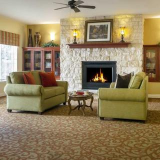 A cozy living room with a stone fireplace, comfortable seating, and warm lighting.