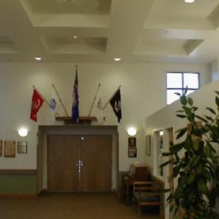 Interior hallway with flags displayed above a doorway, featuring plants and ceiling lighting.