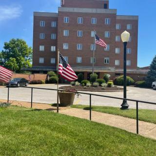 A brick building with American flags and a well-maintained lawn on a sunny day.