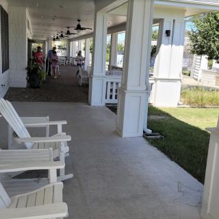 A large porch with white chairs and a view of the garden.