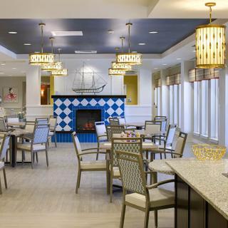 A modern dining area featuring elegant tables and chairs, with a central fireplace and stylish ceiling lights.
