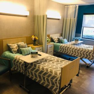 A well-designed hospital patient room featuring two beds, modern furnishings, and a calming color scheme.