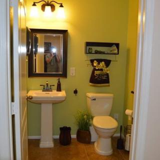 A cozy bathroom featuring green walls, a sink, and decorative accents.