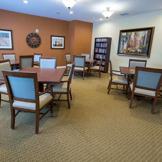A quiet meeting room with tables and chairs, decorated with artwork and a bookshelf.