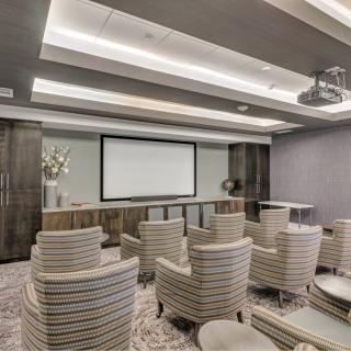 A modern conference room with comfortable seating and a projector screen for presentations.