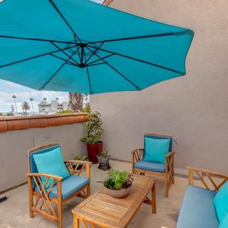 A cozy outdoor patio setup with wooden furniture and a large blue umbrella.