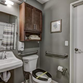 A modern bathroom with a sink, toilet, and wooden cabinet.