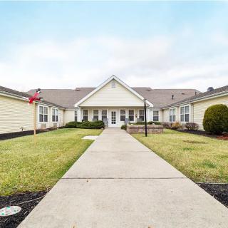 A wide pathway leads to a large residential building surrounded by a well-kept lawn.
