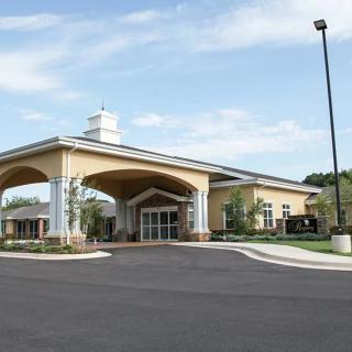A modern church building with an arched entrance and large parking area.