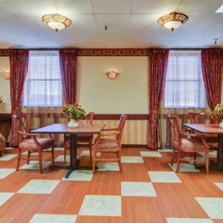 A well-furnished dining room with tables and chairs, adorned with elegant curtains and warm lighting.