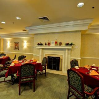 An elegant dining room with tables set for a meal, featuring a fireplace and sophisticated decor.