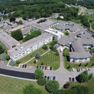 Aerial view of a healthcare facility surrounded by greenery and a parking area.