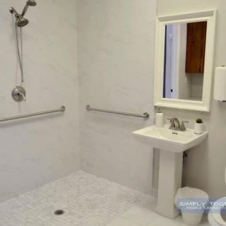 An accessible bathroom with a walk-in shower, sink, and safety grab bars.