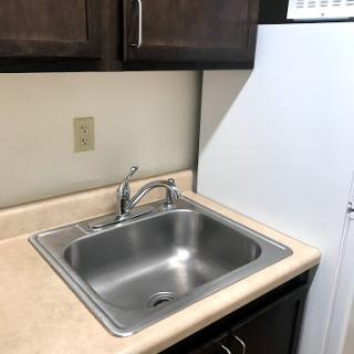 A compact kitchen area featuring a stainless steel sink and a refrigerator.