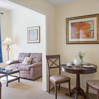 A cozy living and dining area with a sofa, round table, chairs, and artwork on the walls.