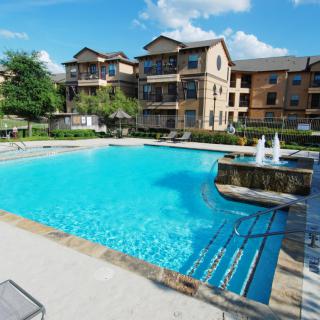 A luxurious apartment complex with a large outdoor swimming pool.