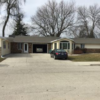 A suburban house with a car parked in the driveway on a clear day.