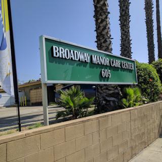 Sign for Broadway Manor Care Center, surrounded by palm trees.