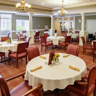 An elegant dining room with neatly arranged tables and chairs, adorned with chandeliers.