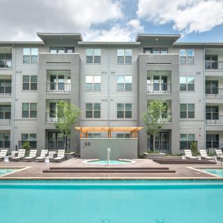 A modern apartment building with a pool in the foreground, showcasing urban residential living.