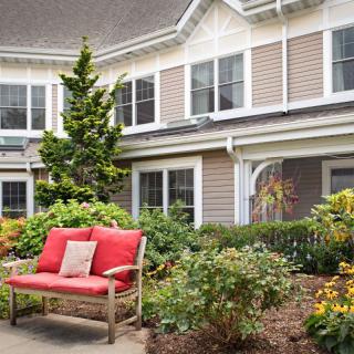 A charming house with a well-maintained garden and a red-cushioned bench.