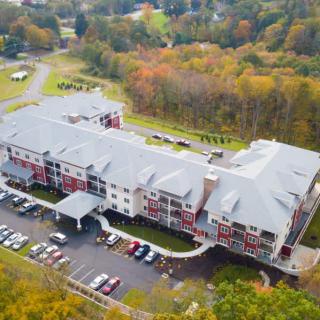 Aerial view of a residential building surrounded by autumn trees.