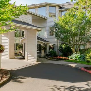 A residential building with a well-maintained driveway and lush landscaping.